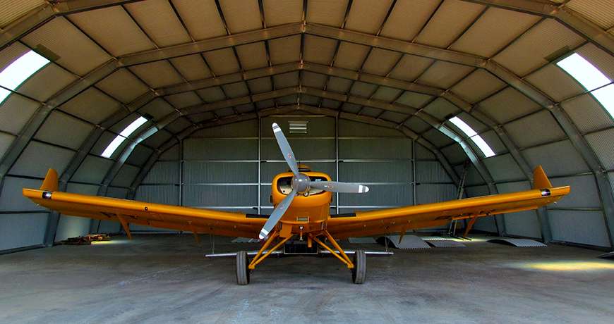 Orange airplane sheltered in a semicircle steel metal hangar